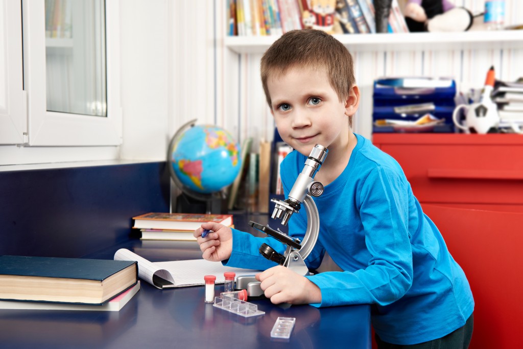 Happy boy with microscope at home